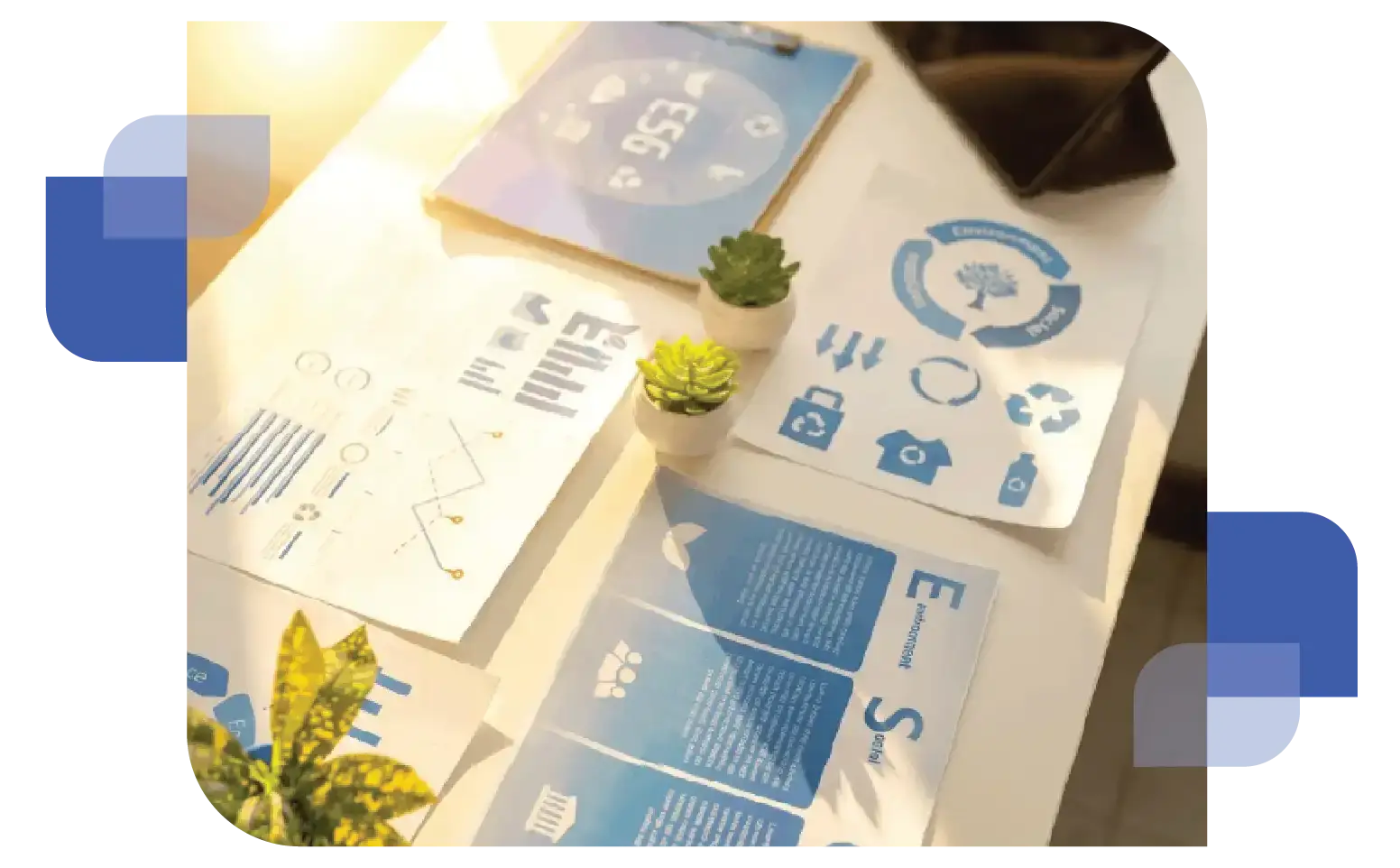 Overhead shot of a workspace with printed sustainability reports, a smartphone, and a tablet showing a dashboard with the text "ESG" and leaf icons, representing environmental data management.